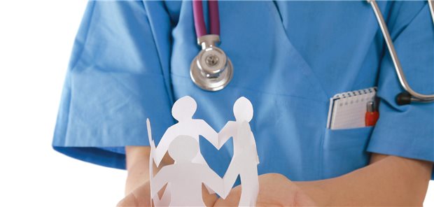 Arzt häät Papierfigürchen in der Hand.