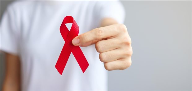 HIV-Remission mit nicht-resistenten Stammzellen erreicht Eine Hand hält die rote Aids-Schleife in die Kamera.