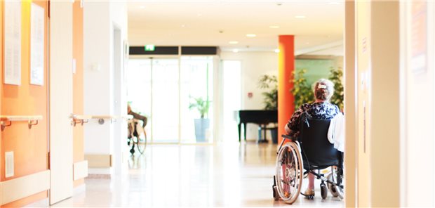 Aufnahme eines Flures in einem Pflegeheim in dem eine Frau in einem Rollstuhl sitzt.