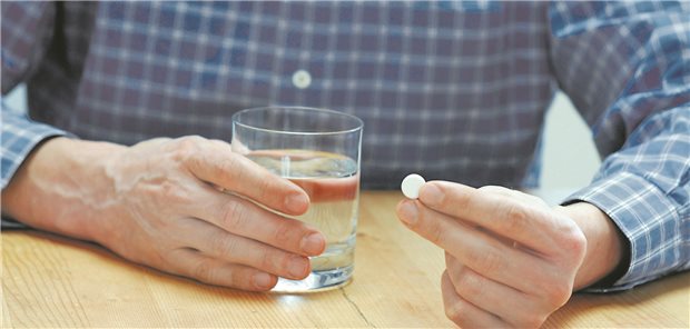Ein älterer Herr nimmt eine Tablette ein.