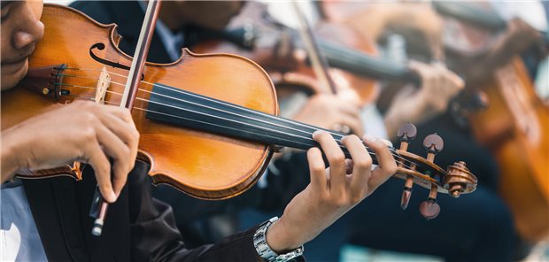 Nahaufnahme eines männlichen Geigers, der als Teil eines Sinfonieorchester klassische Musik spielt. 