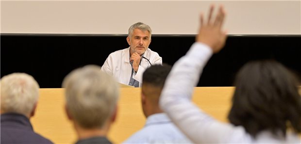 Polymyalgia rheumatica: Immer gleich in die Facharztpraxis! Ein Arzt hält einen Vortrag in einem Kongresszentrum mit Publikum im Hintergrund.