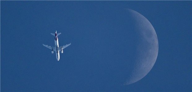 Medizinische Betreuung von Piloten - Auffälligkeiten ist immer nachzugehen Ein Flugzeug wird von unten im Flug fotografiert. Neben dem Flieger ist der sichelförmige Mond.