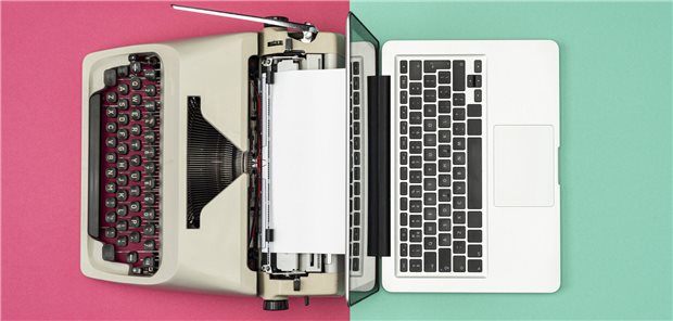 Ein moderner Laptop-Computer Rücken an Rücken mit einer antiken Schreibmaschine.