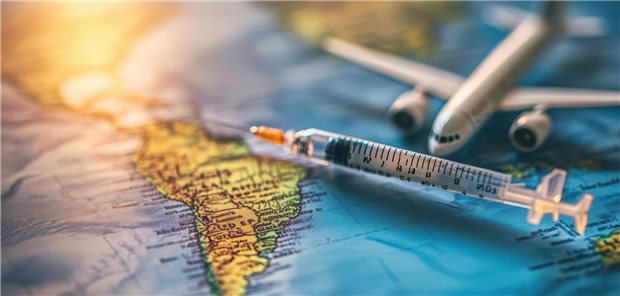 Eine Spritze und ein kleines Spielzeug-Flugzeug liegen auf einer Weltkarte.