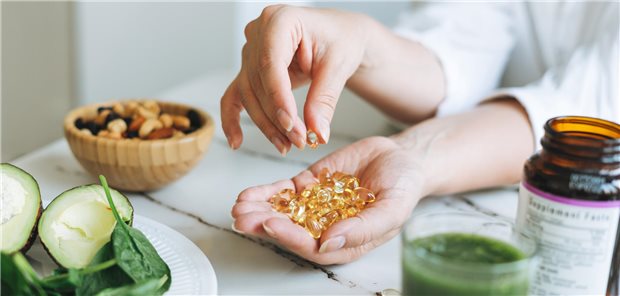 gelbe Kapseln mit Vitamin D vor grauem Hintergrund
