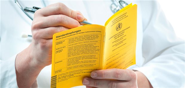 ESC: „Impfen ist vierte Säule der kardiovaskulären Prävention!“ Ein Arzt fühlt die internationale Impfbescheinigung eines Patienten aus.