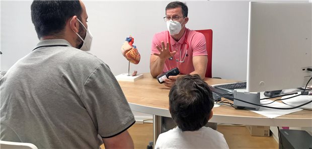 Kinderarzt Dr. Florian Schmidt nutzt die Triaphon-Hotline über sein Telefon für das Gespräch mit einem Patienten und dessen Vater.