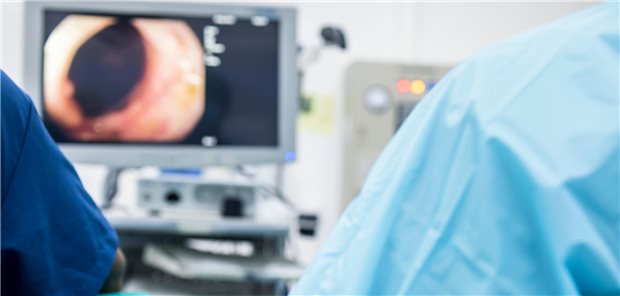 Ein Arzt oder Chirurg in einem hellblauen Schutzkittel führte im Operationssaal des Krankenhauses eine Koloskopie durch.