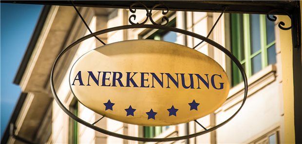 Ein Schild mit der Aufschrift Anerkennung hängt an einer Hauswand.