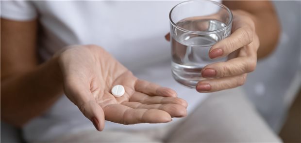Acetylsalicylsäure hat bei Gesunden auch längerfristig keinen präventiven Effekt Nahaufnahme einer älteren Frau, die eine Tablette und ein Glas Wasser in der Hand hält.