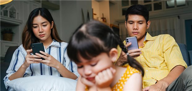 Häufige Mediennutzung der Eltern beeinflusst wohl die Kindesentwicklung Asiatisches kleines Mädchen wird von ihren Eltern zu Hause ignoriert.