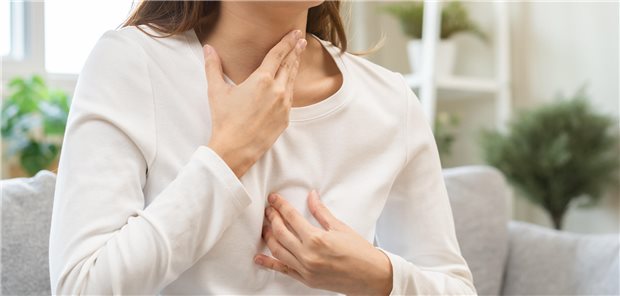 Eine junge Frau leidet unter gastroösophagealen Beschwerden, weswegen sie sich nach dem Essen aufgrund von Verdauungsproblemen mit der Hand auf die Brust hält.
