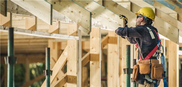 Ein Bauunternehmer bei der Arbeit an einem Hausbau aus Holz.
