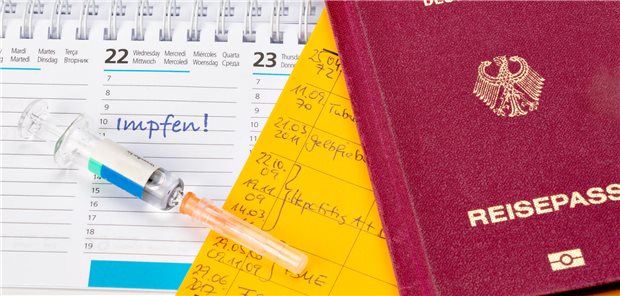 Auf einem Kalender liegen eine Spritze und ein Reisepass.