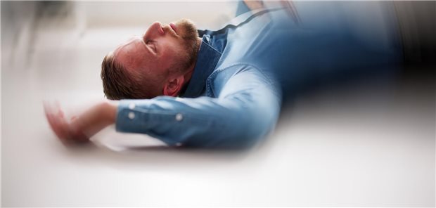 Ein Mann liegt am Boden als wäre er gefallen. Das Bild ist verschwommen als würde es sich drehen.