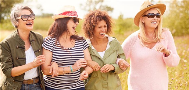 5 Mythen rund um die Perimenopause: Eine Gynäkologin klärt auf Vier mittelalte Frauen laufen gemeinsam über eine Wiese und lachen.