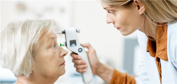 Augenärztin misst den Augendruck mit einem modernen Tonometer bei einem älteren Patienten in der Arztpraxis.