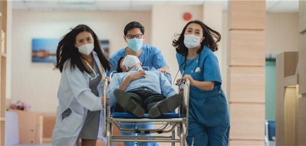 Ärztin und Pflegekräfte schieben einen Patienten durch einen Krankenhausflur.