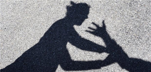 Ein Mann schlägt nach einer Frau, von beiden sind nur die Schatten zu sehen.