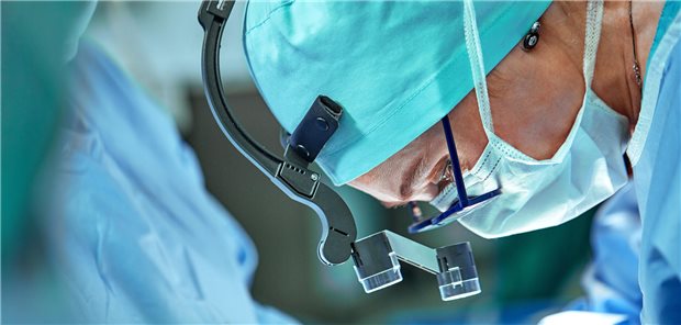 Nahaufnahme des Gesichtes einer Chirurgin im Operationssaal beim Dürchführen eines operativen Eingriffes.