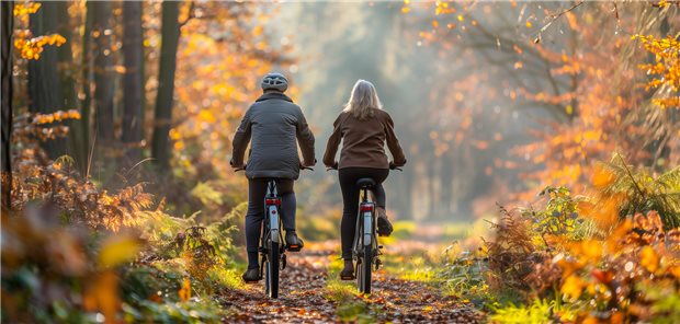 Zwei Menschen auf dem Fahrrad durch den Wald.