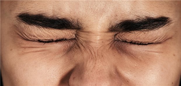 „Gender Pain Gap“ – wenn Schmerzen nicht ernst genommen werden Eine Frau kneift die Augen zusammen.