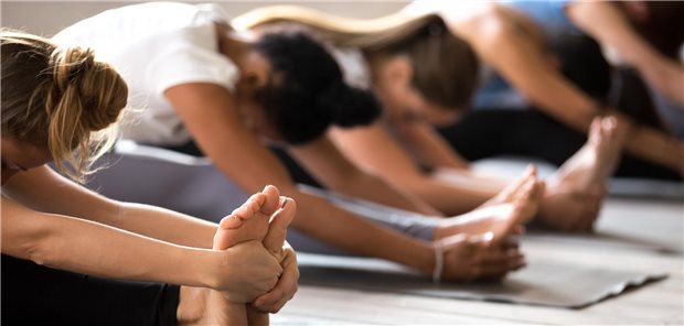 Expertenkonsens: Dehnen verbessert die Beweglichkeit, beugt aber kaum Verletzungen vor Eine Gruppe junger Frauen führen Dehnübungen im Fitnesstudio durch.