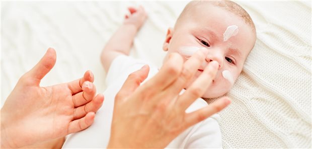 Tägliche Hautpflege könnte Säuglinge doch vor atopischer Dermatitis schützen Eine Mutter cremt das Gesicht von ihrem Baby mit Hautcreme ein.