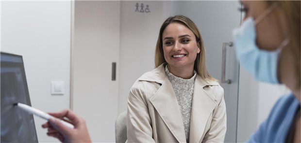 Humor macht Alltag in der Arztpraxis stressfreier Patienten lacht. während MFA ihr etwas am PC zeigt.