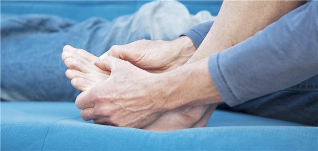 Ein Mann greift sich an den Fuß.