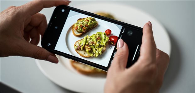 Eine Frau fotografiert ihr Essen mit dem Handy.