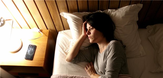 Schlechter Schlaf bei Fibromyalgie: Evidenz zur Therapie weiter dürftig Eine Frau, die unter Schlaflosigkeit leidet, liegt wach in ihrem Bett und bertrachtet das angeschaltete Licht.
