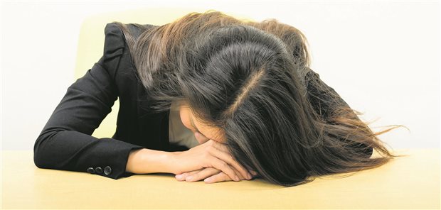 Eine junge Frau liegt mit dem Kopf auf einem Tisch