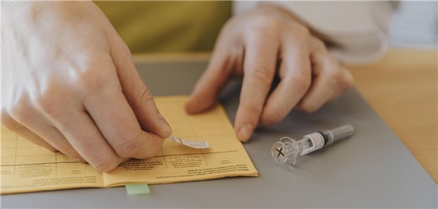 Eine Ärztin klebt den Sticker von einer Impfspritze in einen Impfpass.