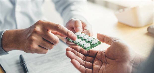 Ein Arzt verschreibt einem männlichem Patienten Tabletten.