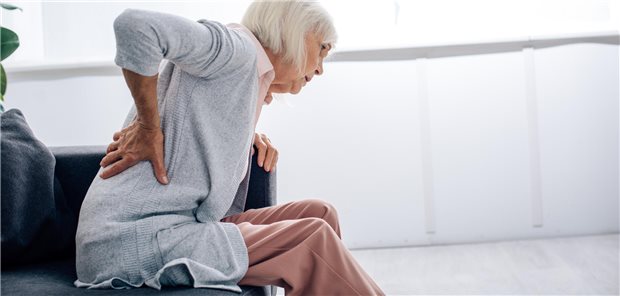 Akupunktur offenbar mit Zusatznutzen bei älteren Menschen mit chronischen Rückenschmerzen Seitenansicht einer älteren Frau mit Rückenschmerzen in ihrer Wohnung.