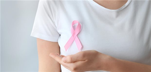 Frau hält rosa Schleife vor ihre Brust.