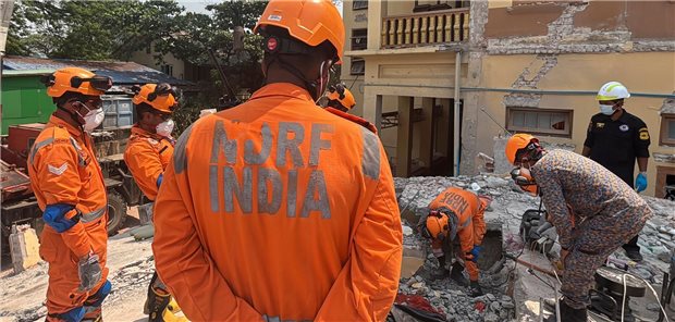 Indische und myanmarische Rettungskräfte versuchen, eine Leiche aus dem buddhistischen Kloster U Hla Thein in Mandalay zu tragen.