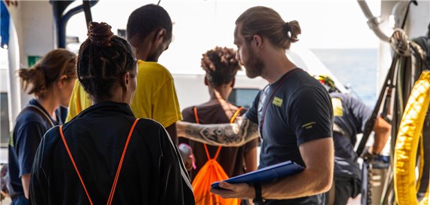 Jörg Schmid (re.) klärt die familiären Konstellationen unter den Passagieren. 70 von insgesamt mehr als 270 Geretteten können an die Küstenwache übergeben werden. Doch wer ist besonders vulnerabel? Für den Arzt auf Seenotrettungsmission eine schwierige Entscheidung.