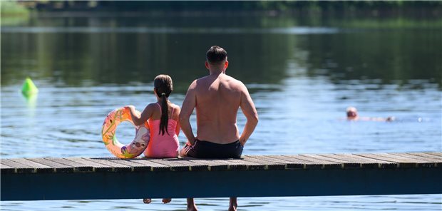 Steigende Temperaturen sorgen für Ausbreitung von Vibrionenarten Ein Vater und seine Tochter sitzen am Steg eines Badesees