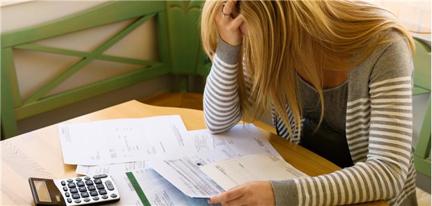 Verzweifelte Frau grübelt über Rechnungen.