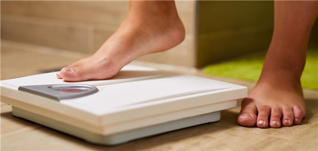 Ein Mensch tritt auf eine Waage