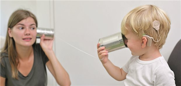 Gentherapie schlägt Cochleaimplantat bei angeborener Taubheit Ein Kleinkind trägt ein Cochleaimplantat und kommuniziert mit seiner Mutter über ein Dosentelefon.