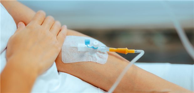 Arm eines Patienten mit IV-Kanüle über die er eine Infusion mit Medikamenten erhält.