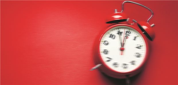 Ein roter Wecker liegt auf einem roten Untergrund und wackelt.