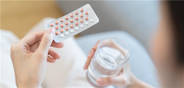 Eine junge Frau mit einer Packung Antibabypillen in der Hand.