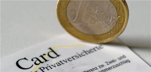 Eine Münze steht auf einer PKV-Versichertenkarte