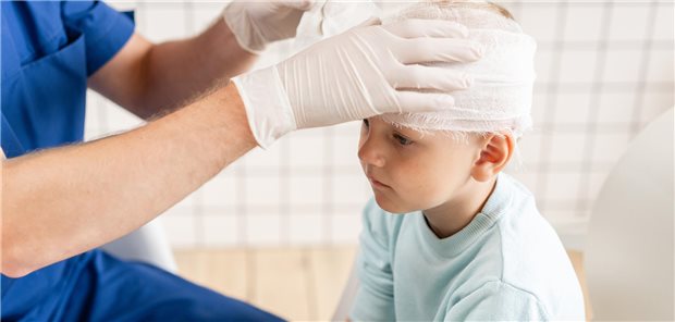 Schädelhirntrauma: Präventionsprogramm zeigt erste Erfolge in Schulen Ein Arzt verbindet den Kopf eines Kindes.