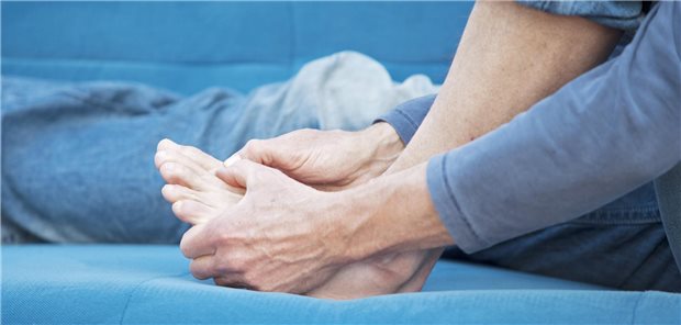 Eine Frau hält sich den Fuß fest.